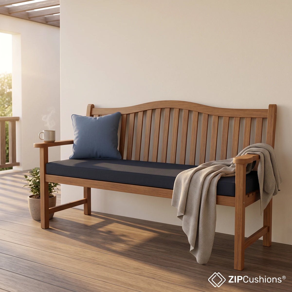A wooden outdoor patio bench with a dark navy cushion and a blue throw pillow, styled with a beige throw blanket on a warm patio. The ZIPCushions logo is visible in the bottom right corner. - view 5