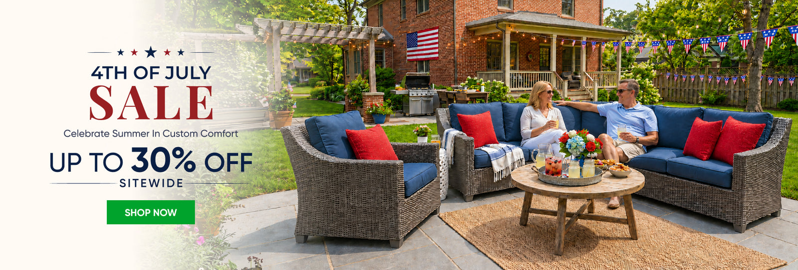 Couple lounging on navy cushioned wicker patio set with red pillows, US flag on brick home; 4th of July sale, 30% off.